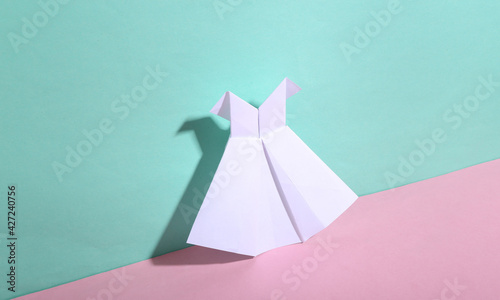Origami white dress on blue-pink pastel background. Minimalism. Trendy shadow. Creative layout. © splitov27