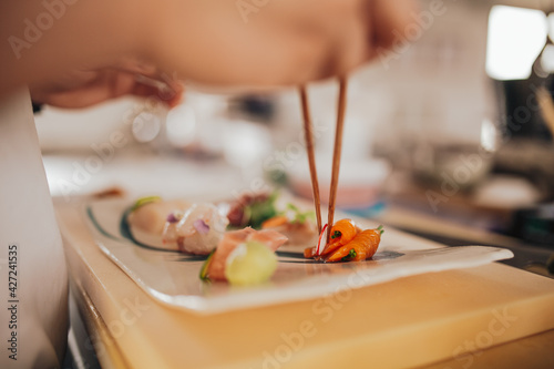 Fotografie Close up shot of a professional sushi chef preparing sashimi in a restaurant