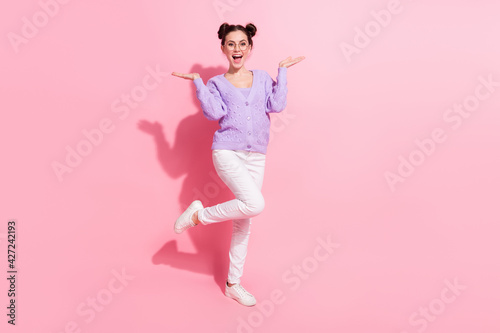 Full length body size photo of cheerful girl with bun laughing overjoyed isolated on pastel pink color background