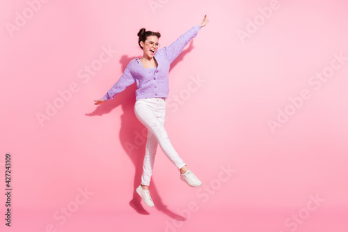 Full length body size photo of cheerful girl jumping up playful smiling happy isolated on pastel pink color background
