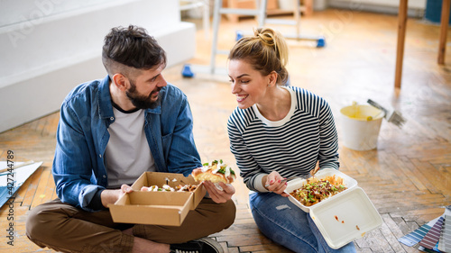 Vászonkép Couple eating lunch indoors at home, relocation, diy and food delivery concept