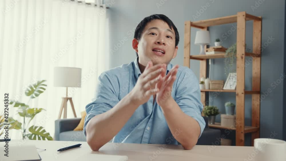 Young Asia businessman using computer laptop talk to colleagues about plan in video call meeting while working from home at living room. Self-isolation, social distancing, quarantine for corona virus.