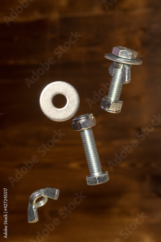falling screws, washer and retaining nut on blurred brown background