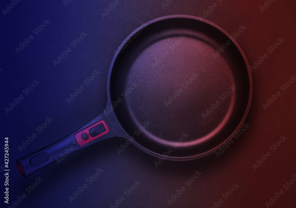Frying pan with non-stick coating in red blue neon light. Top view Frying pan with non-stick coating in red blue neon light. Top view