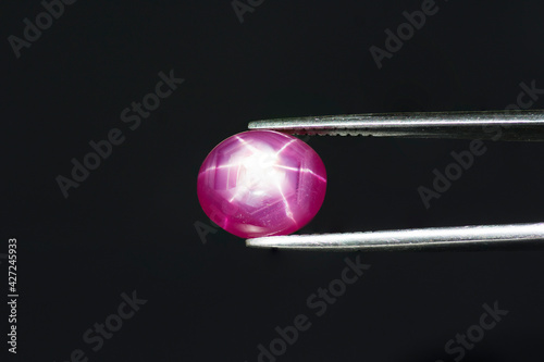 Foto Natural Red 6 rays star ruby cabochon gemstone in tweezers