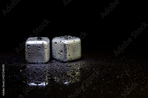 Fototapeta Naklejka Na Ścianę i Meble -  Stainless steel cubes simulating ice for cooling drinks on a black surface with a reflection.