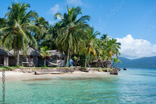 Palm trees on a tropical beach with crystal clear water to relax and cabanas to rest