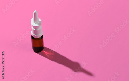 Nasal spray with shadow on pink background. Minimalistic medicine still life