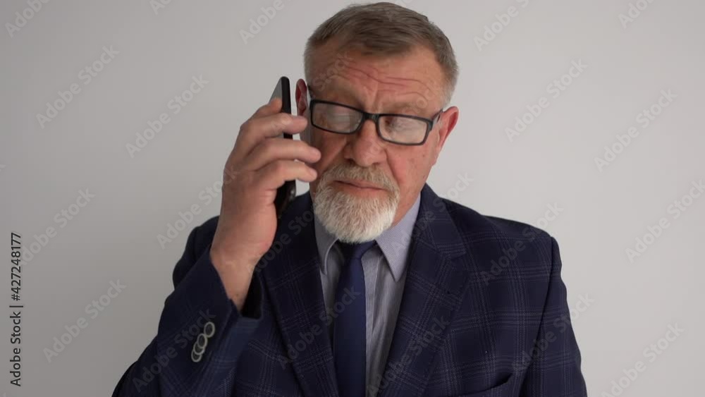 Elderly man talking by mobile phone on white background. Portrait of old caucasian businessman using smartphone for calling. Mature lawyer negotiating over the phone Elderly man talking by mobile phone on white background. Portrait of old caucasian businessman using smartphone for calling. Mature lawyer negotiating over the phone