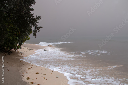St. James, Barbados - April 10 2021: Thick ash from St. Vincent and the Grenadine's Soufriere volcano eruption turns the sky and ocean grey on an east coast beach with a thick unbreathable haze. 