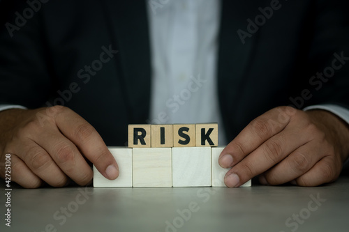 Businessman in suit hold wooden cubes with risk word.