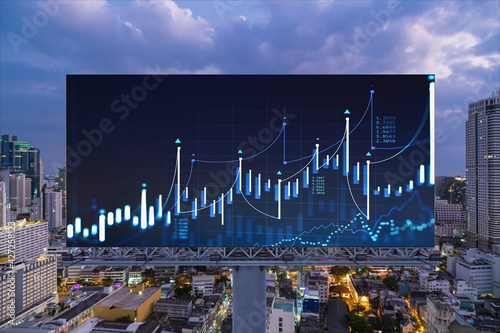 FOREX graph hologram on billboard, aerial night panoramic cityscape of Bangkok. The developed location for stock market researchers in Southeast Asia. The concept of fundamental analysis photo