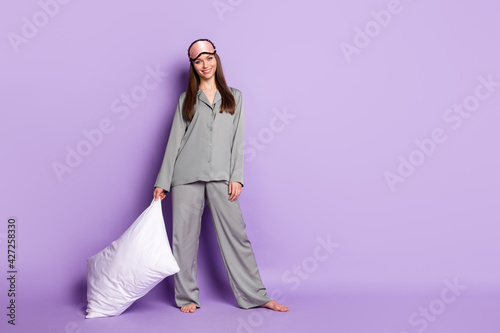 Full length body size view of attractive cheerful girl wear pajama carrying soft pillow bedtime isolated on violet purple color background