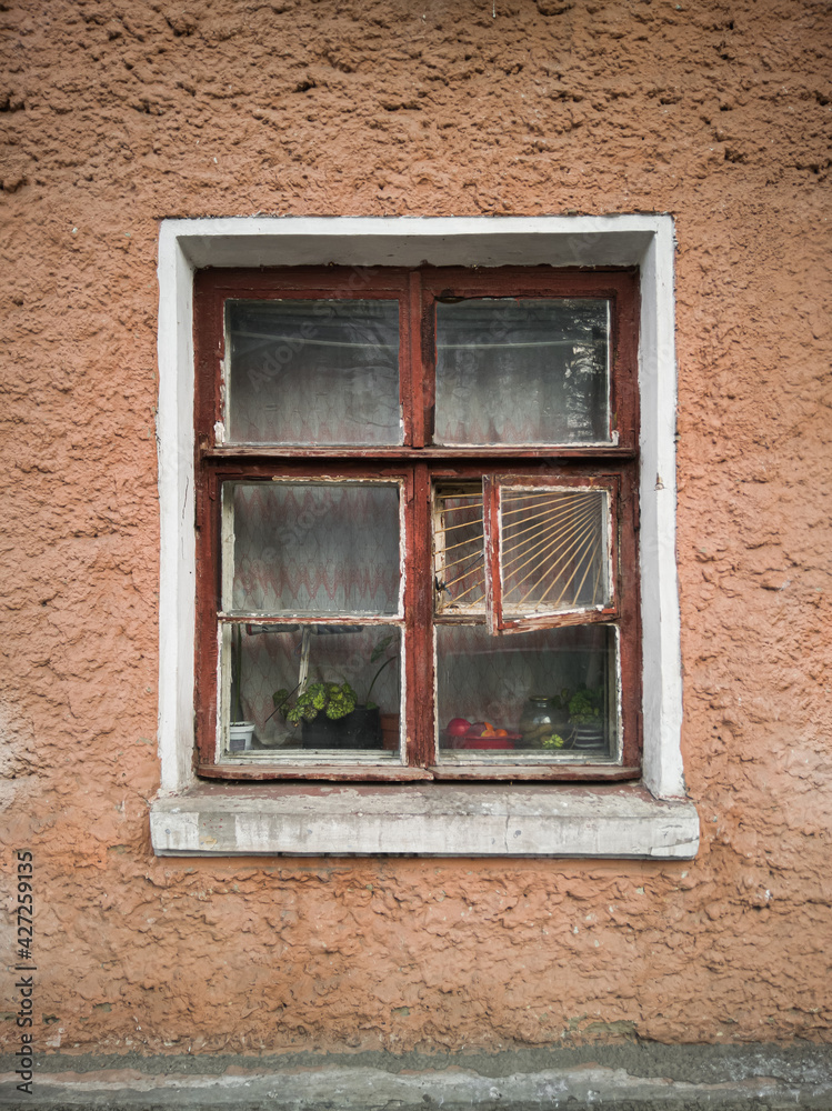 Old vintage wooden window on the orange wall of an old house.