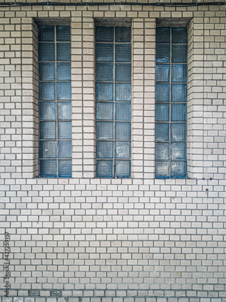 Three narrow windows on the wall of an old building lined with ceramic tiles. Three narrow windows on the wall of an old building lined with ceramic tiles.