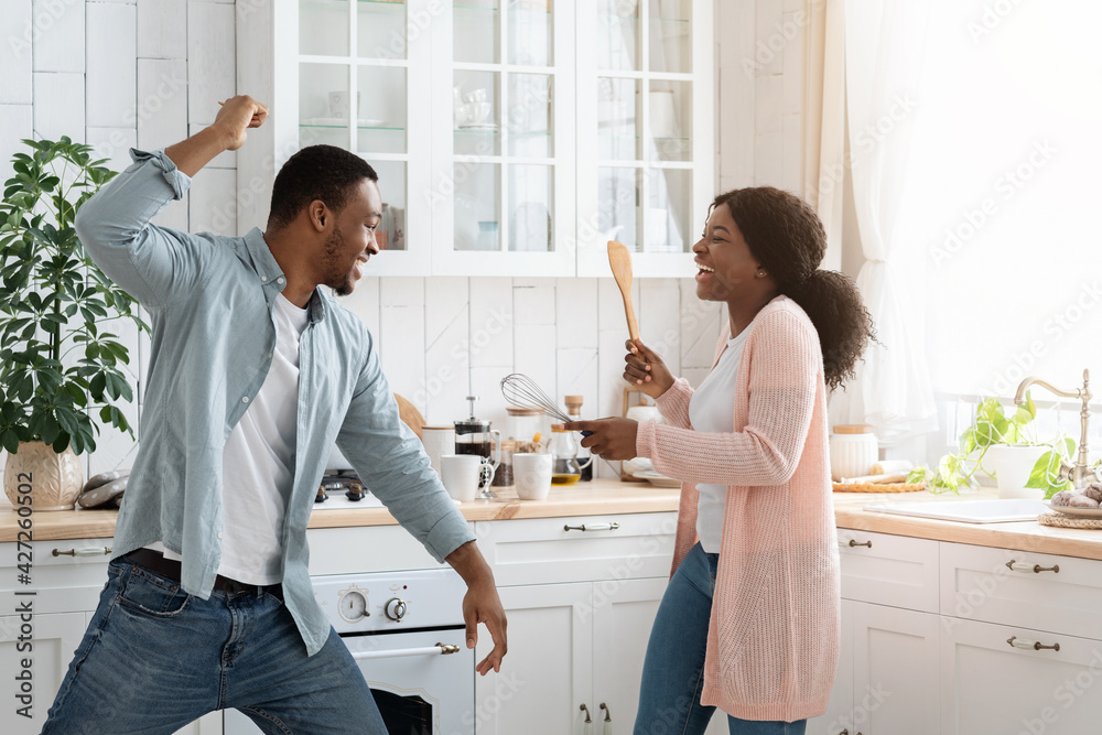 Domestic Fun. Black spouses playfully fighting in kitchen, using spatulas as weapons Domestic Fun. Black spouses playfully fighting in kitchen, using spatulas as weapons