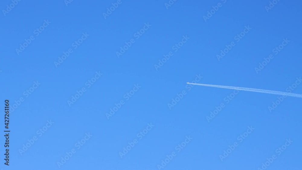The jet plane flies quickly against the background of the blue sky. Summer sky landscape with sunlit time lapse. Beautiful background with blue sky in clear weather. Timelapse 4K video. The jet plane flies quickly against the background of the blue sky. Summer sky landscape with sunlit time lapse. Beautiful background with blue sky in clear weather. Timelapse 4K video.