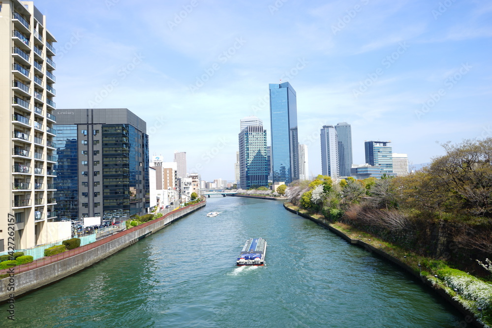 Fototapeta premium Osaka skyline along with Neya river (Neyagawa) in Japan . Panoramic view. - 日本 大阪府 寝屋川 大阪のビル 水上バス
