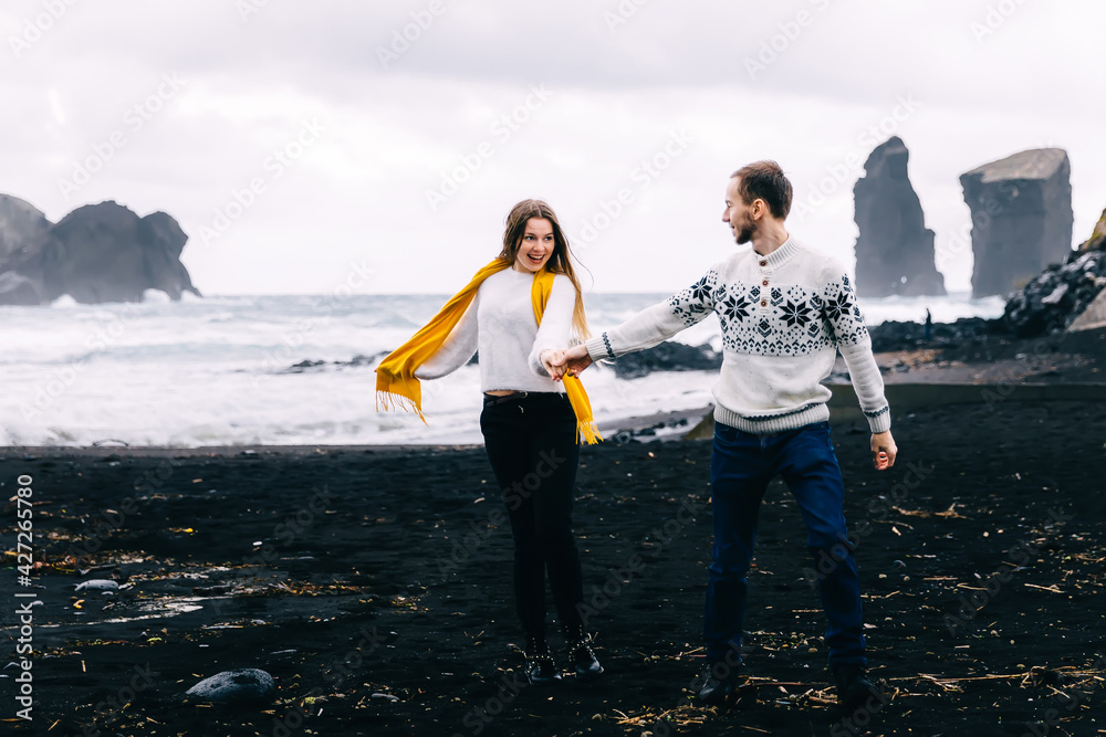 Icelandic tourist couple walking to the black sand beach south coast. Happy woman and man visiting tourist attraction. Icelandic tourist couple walking to the black sand beach south coast. Happy woman and man visiting tourist attraction.