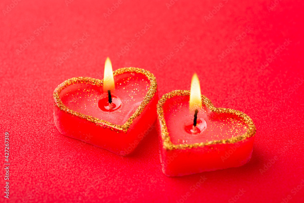 Two heart shaped burning candles, close up on red background. Symbol of mutual love. Two heart shaped burning candles, close up on red background. Symbol of mutual love.