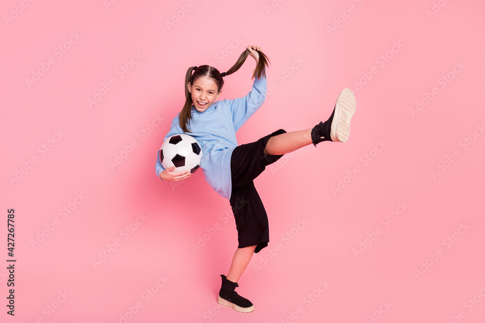 Full length body size photo of schoolgirl in sport outfit keeping ball practising karate isolated pastel pink color background