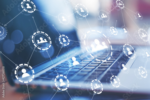 Multiple application hologram icons with a laptop on the desk in the background. Social media and communication concept, double exposure