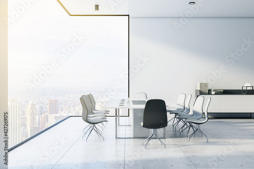 Sunny conference room on city skyscraper high floor with modern monochrome style furniture, light marble floor and great city view from glass wall