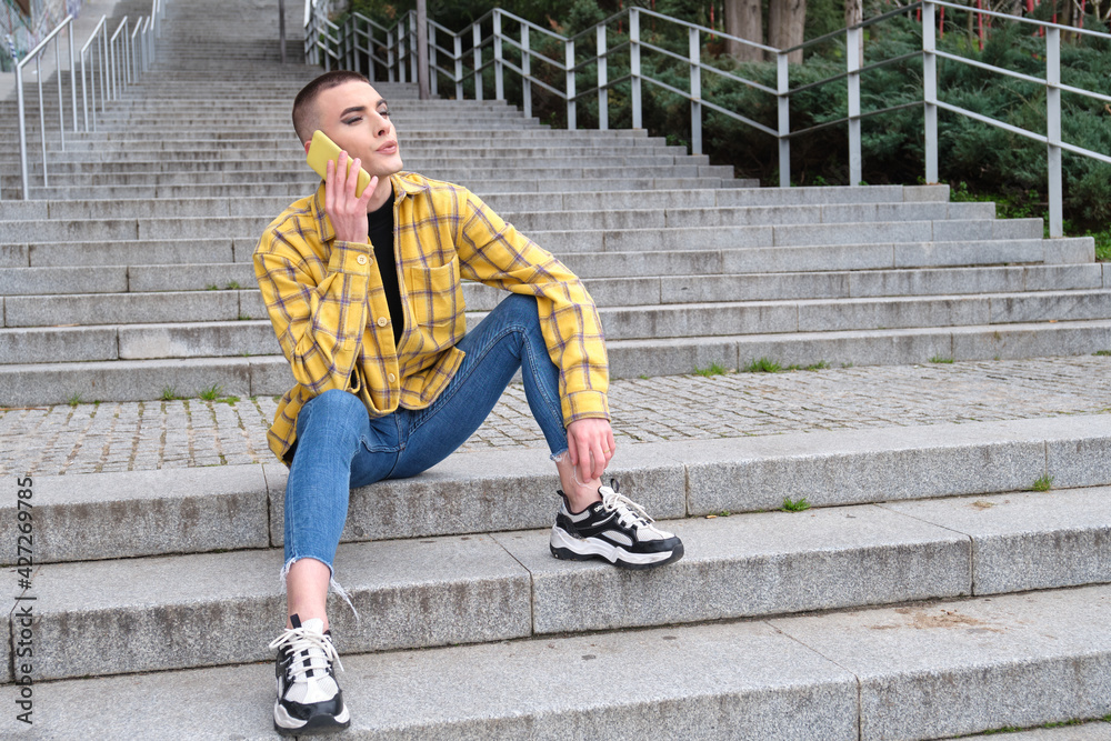 Young non binary person talking by his smartphone annoyed. Make up androgynous person. Young non binary person talking by his smartphone annoyed. Make up androgynous person.