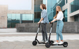 Young guy and lady having ride on electric kick scooter