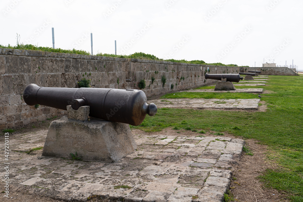 Cast iron Napoleon era cannons and heavy defensive wall part of fortification of an ancient city wall, built around 1800–1814 by Jazzar Pasha, left, Akko, Acer, Israel