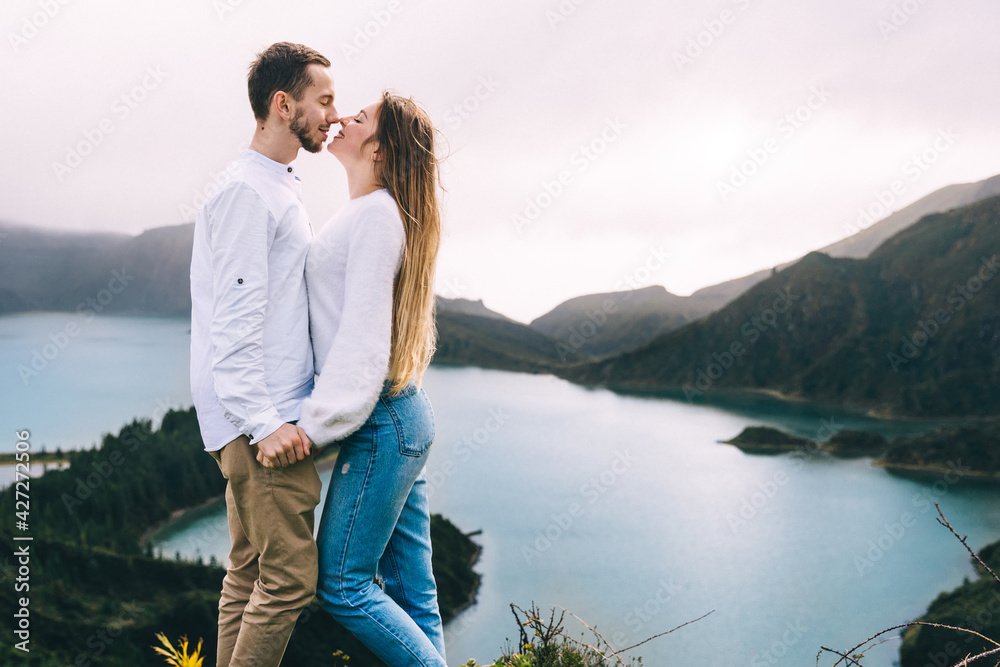 Φωτογραφία Young couple kissing on the background of a lake in a beautiful landscape