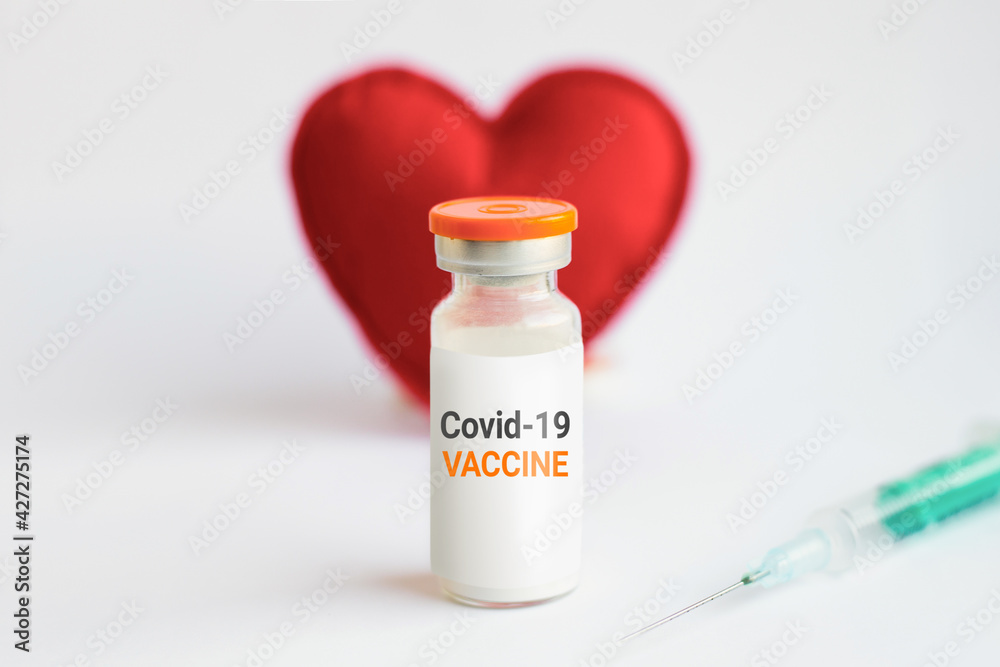 Vaccination concept. Medical jar with coronavirus vaccine on red heart background Vaccination concept. Medical jar with coronavirus vaccine on red heart background