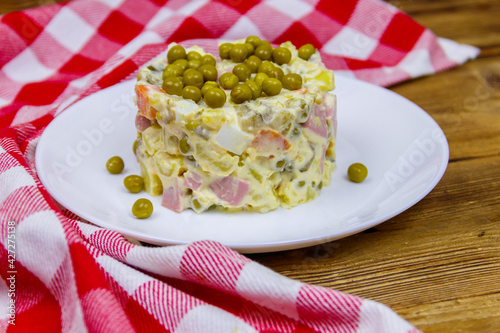 Traditional Russian festive salad Olivier on wooden table