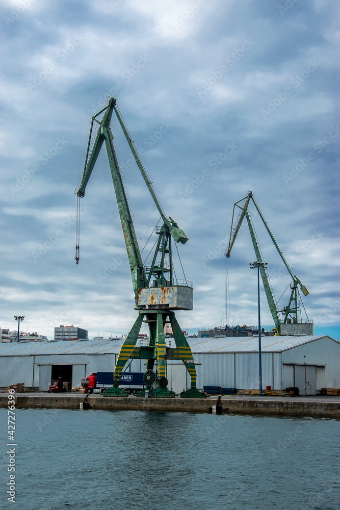 Grúa industrial de un puerto y edificios de almacenamiento junto a los muelles en una ciudad del Atlántico español