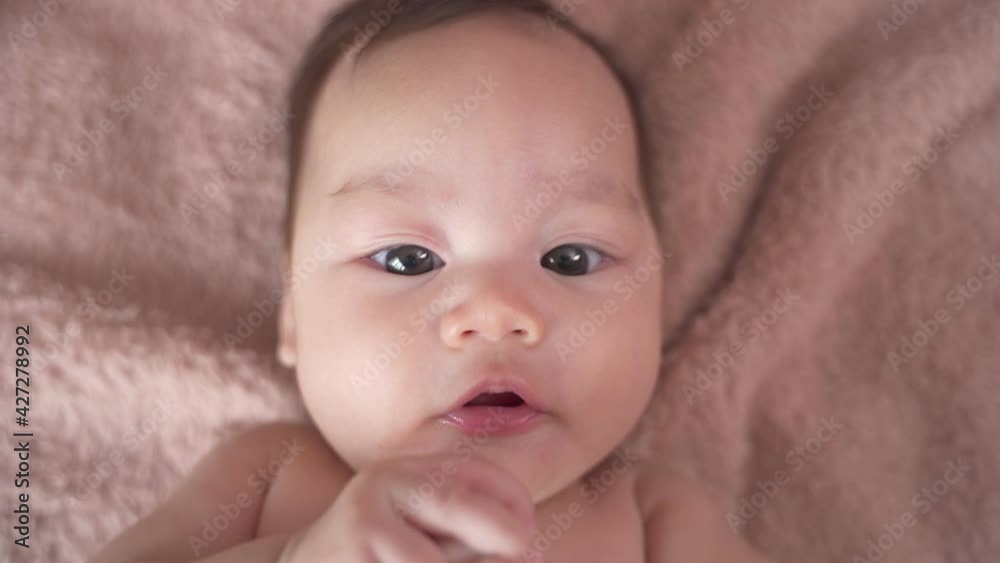 asian baby infant laying down on soft fur bed happy and smile. 3 months old baby facial laughing expression. asian baby infant laying down on soft fur bed happy and smile. 3 months old baby facial laughing expression.