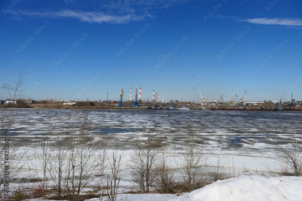 Spring ice on the river. Plant by the river and sand mining. High quality photo