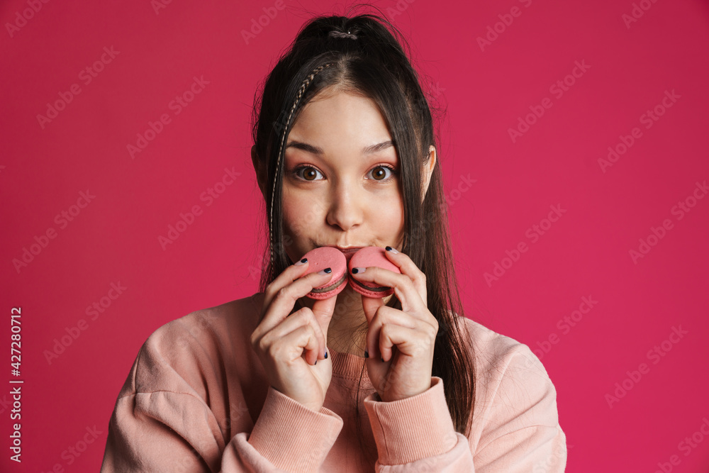 Asian brunette happy woman smiling while posing with macaroons Asian brunette happy woman smiling while posing with macaroons