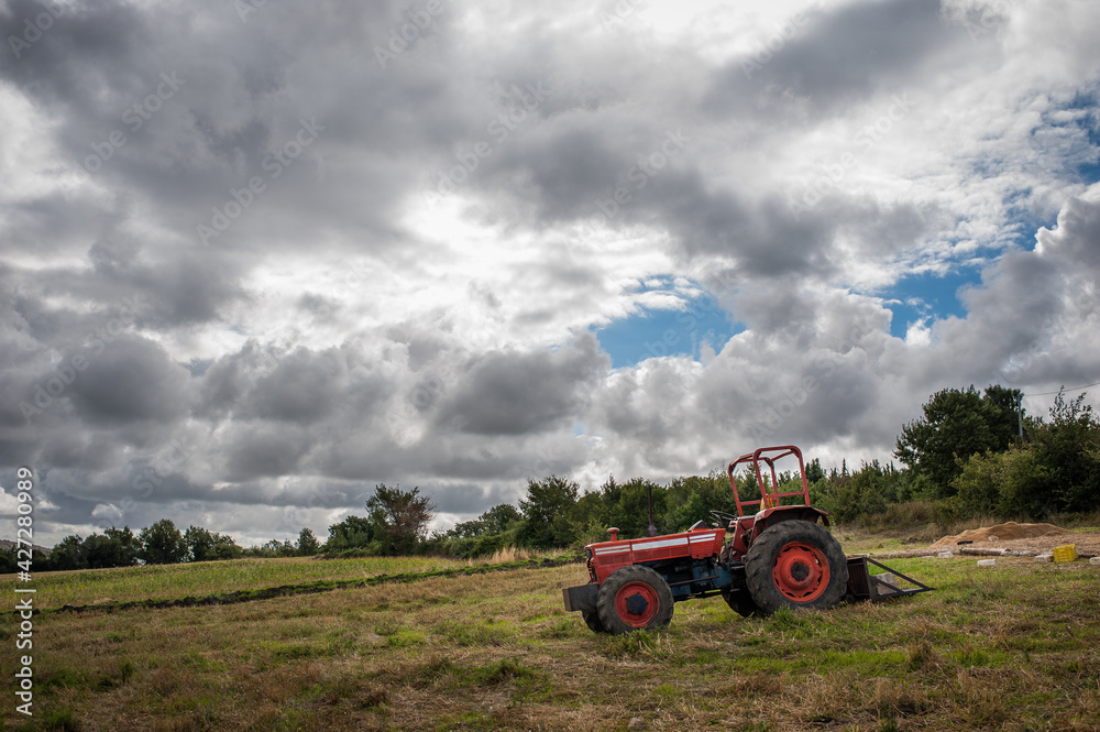 Un tractor en un campo en un dia nublado Un tractor en un campo en un dia nublado