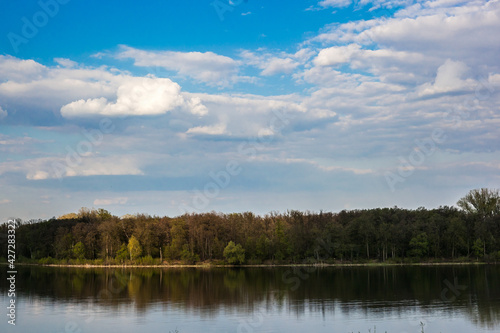 classic spring landscape, trees reflected in the water surface of a calm lake