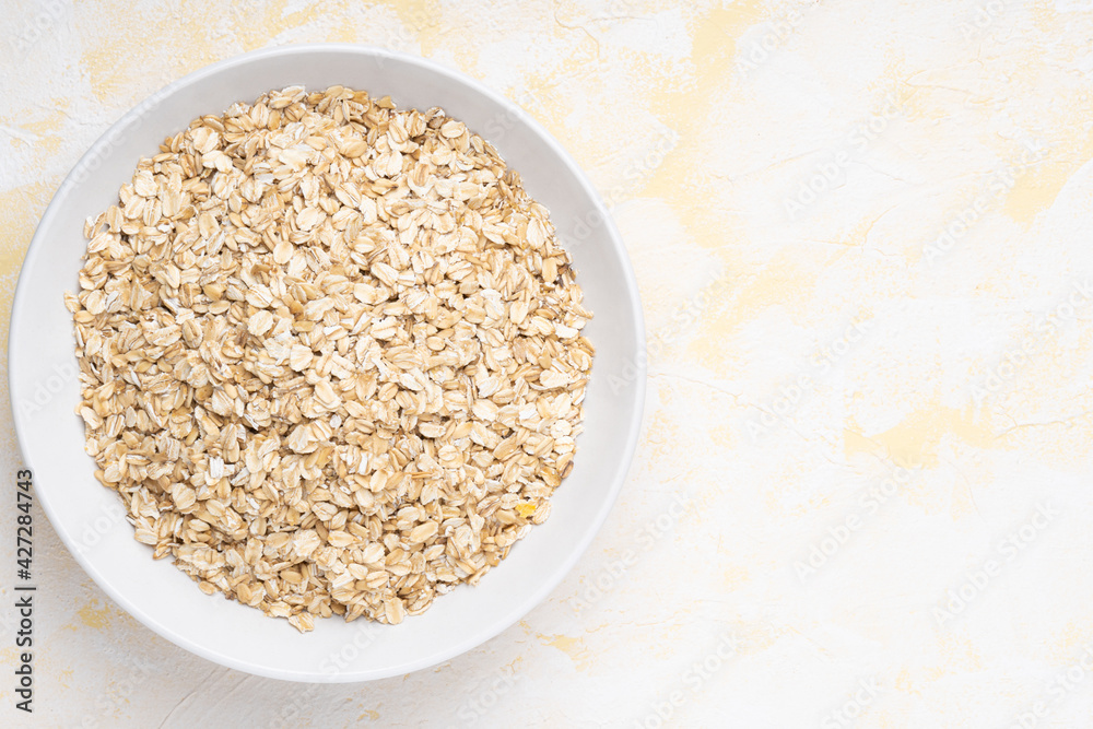 Oat flakes in a white plate on a yellow cement background Oat flakes in a white plate on a yellow cement background