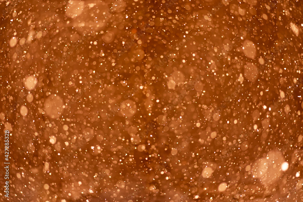 Beautiful blurry sparkles on orange background. Liquid soap in bottle close up