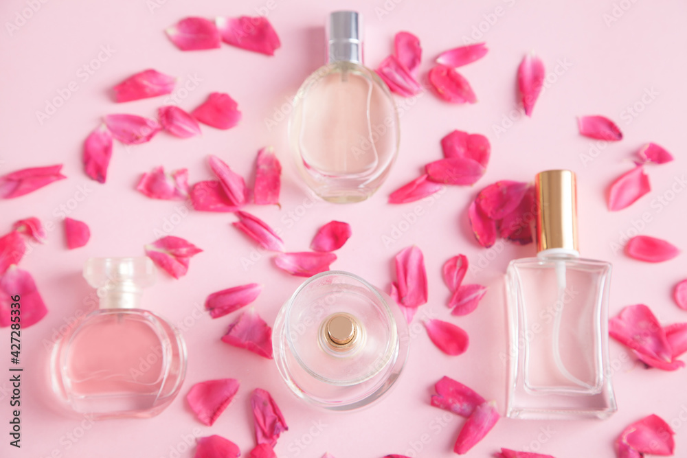 Beautiful womens perfumes, against the background of isolated pink. Wrapped in beautiful rose petals. Beautiful womens perfumes, against the background of isolated pink. Wrapped in beautiful rose petals.