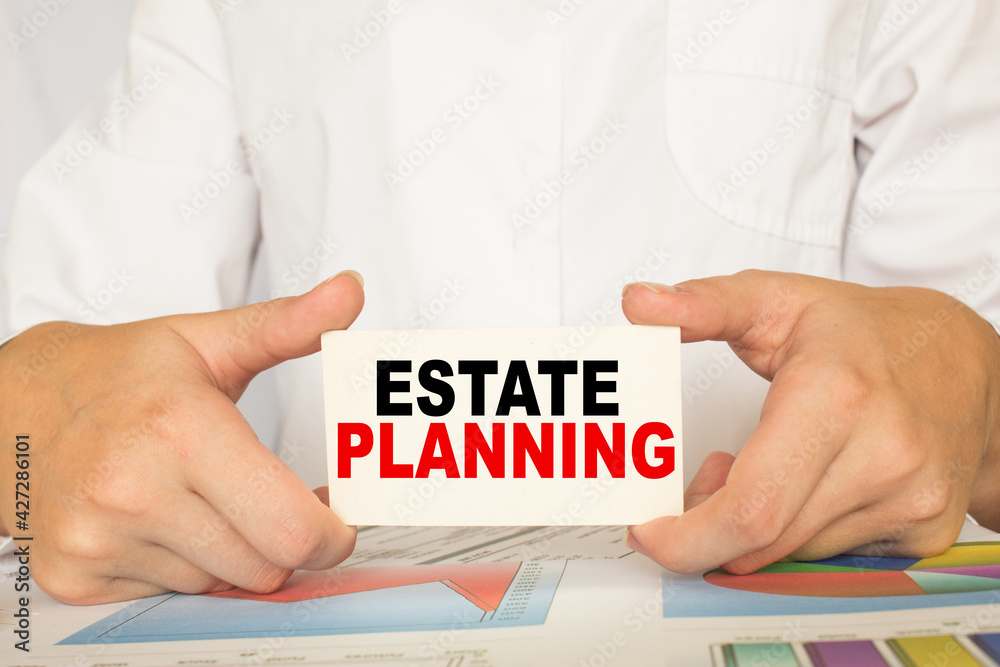 a man in the office holds a card with text ESTATE PLANNING . business concept a man in the office holds a card with text ESTATE PLANNING . business concept