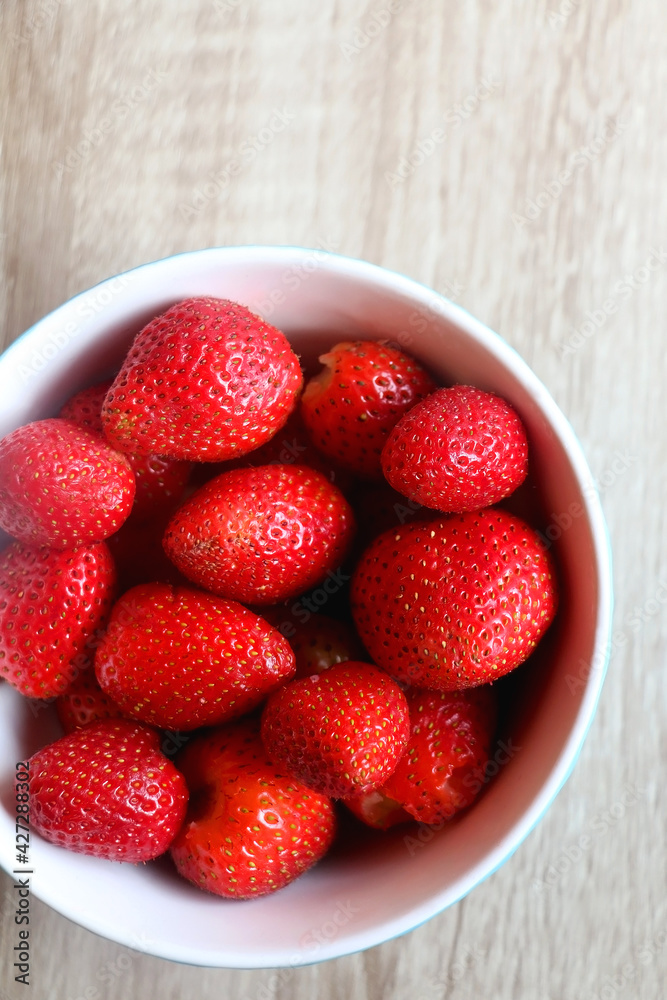 Bowl of fresh strawberries on a table. Flat lay. Bowl of fresh strawberries on a table. Flat lay.