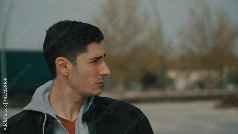 Hombre indeciso y preocupado, pero luego camina con confianza hacia adelante, hombre con chaqueta negra y capucha gris caminando de frente, hombre con cabello negro caminando
