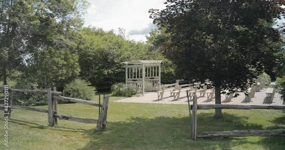 Walking across a lawn through a wood fence surrounded by trees to reveal the wooden pergola of the outdoor wedding ceremony venue at the Strathmere Wedding and Event Centre. Walking across a lawn through a wood fence surrounded by trees to reveal the wooden pergola of the outdoor wedding ceremony venue at the Strathmere Wedding and Event Centre.