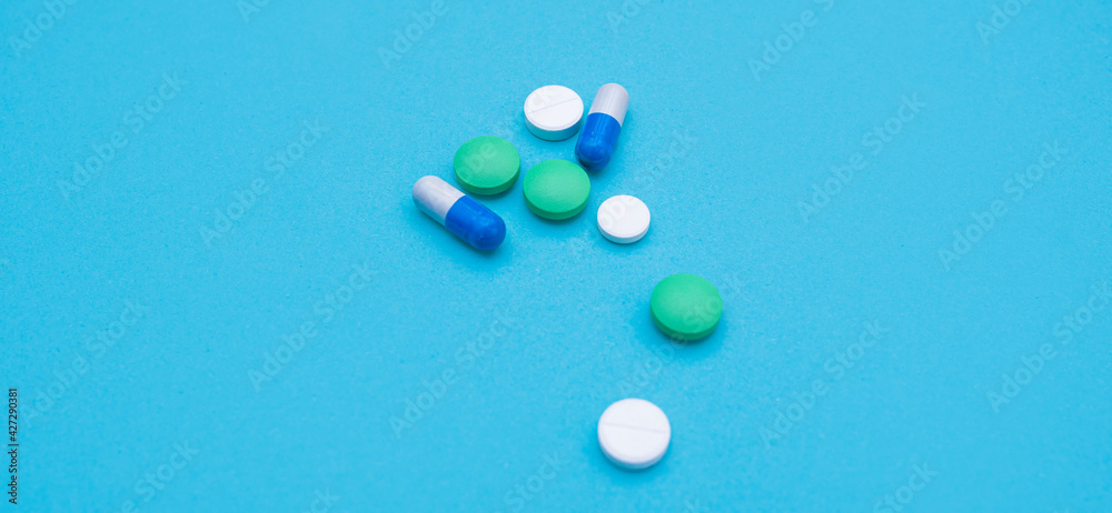 Several pills, green, white, capsules on a blue background. Biological food additives, antibiotics, pain relievers. Baner for design. top view. Flat lay, copy space for text. selective focus