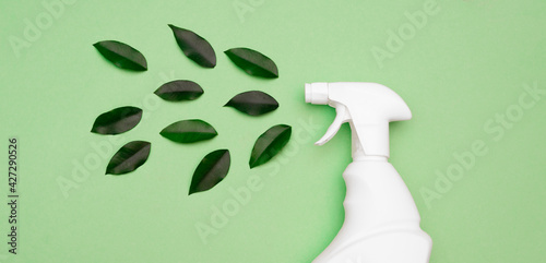 Eco style cleaning concept. White bottle Spray for daily spring cleaning sprays green leaves on a green background close-up. Environmentally friendly cleaning products. top view. Flat lay. copy space