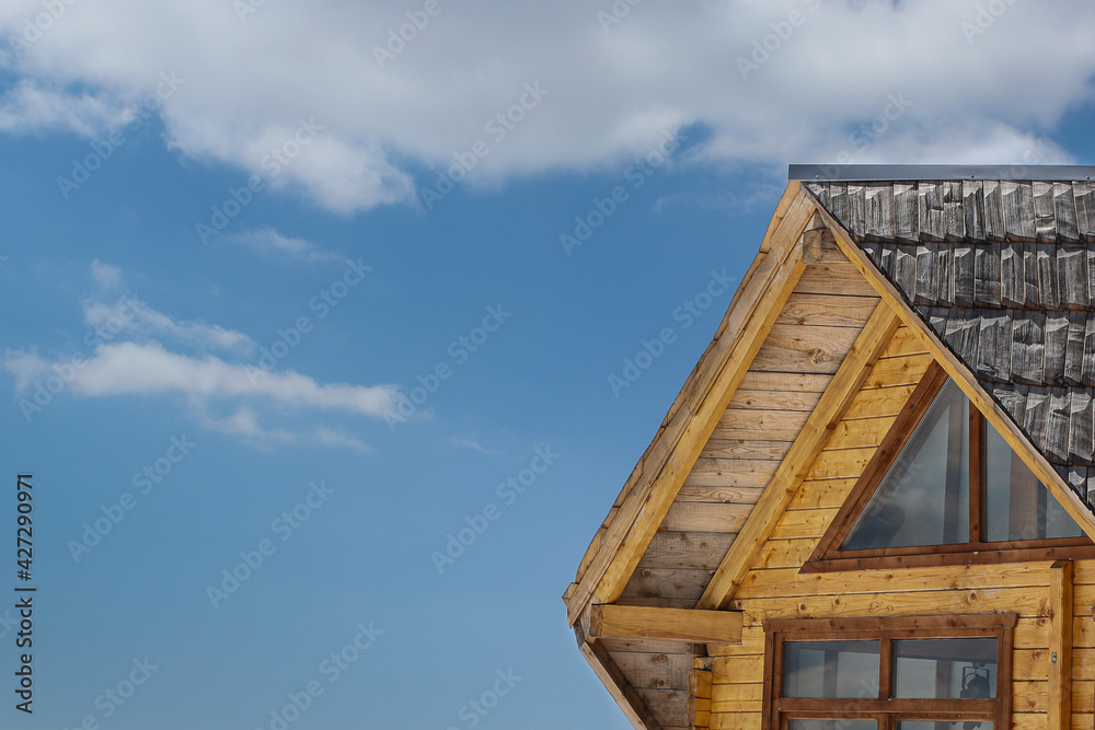 Part Of A Exterior Of A Wooden Mountain House Against The Blue Cloudy Sky Part Of A Exterior Of A Wooden Mountain House Against The Blue Cloudy Sky