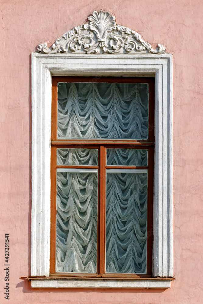 Rectangular window with a bas-relief on the background of a pink stucco wall. From the windows of St. Petersburg series.